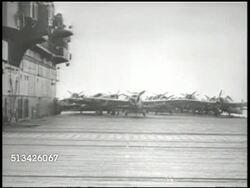 1940s: UNITED STATES NAVY:  VS U.S. Navy carrier ship at sea, Pacific Ocean, POV elevator descending from deck w/ fighter airplanes, to lower level w/ Corsairs, engineer checking fighter plane engine. WWII, Pacific Front Instructional Video