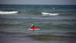 Young boy floats on boogie board in ocean alone Stock Footage