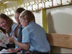 MS Three girls wearing school uniforms, sitting on bench, talking, laughing  and looking through books / Great Yarmouth, England, United Kingdom Stock Footage