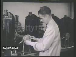 1935: RESEARCH LABORATORY: WS Carbon chemist walking across, checking row of radiators in lab. VS Male chemist checking corrosion on aluminum heads, pulling out rusted metal plates from radiator pipe opening. Corrosion testing Instructional Video