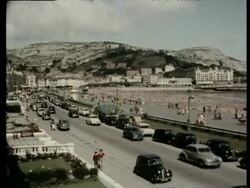Look at Wales Archive: Seaside resort, beach, cars and buses on seafront, Llandudno, Wales, United Kingdom. 1957. Stock Footage