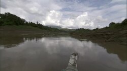 A boat with an anchor on its bow glides down a calm river. Stock Footage