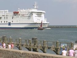 WS People walking on beach with ferry ship moving on river / Warnemuende near Rostock, Mecklenburg-Western Pomerania, Germany Stock Footage
