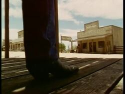 Pair of Cowboy boots walk past and away from camera, left to right, Western town, USA Stock Footage