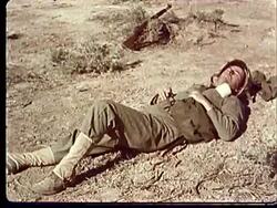 1950s Soldier lying on his back sleeping in desert / Rifle lying in sagebrush beside soldier at Camp Desert Rock at Nevada Test Site / Nye County, Nevada, USA Stock Footage