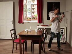 WS PAN Split screen showing woman drilling hole through neighbor's wall / Berlin, Germany Stock Footage