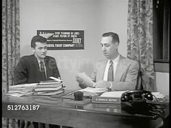 1953: PENNSYLVANIA: LEVITTOWN LOANS: INT Bank Treasure 'Mr. Moyer'  office w/ young adult male sitting, SOT 'Mr. Moyer' saying he has loan approved for his new car, handing man check, congratulating him on new baby. Instructional Video