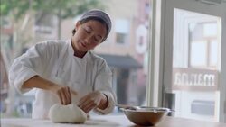 Pastry chef rolls dough in flour and shapes with hands in bakery window Stock Footage