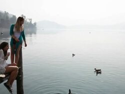 Boom as teenage girls feed ducks from lake pier Stock Footage