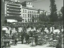 1948: ATHENS CITY: HA XWS Athens City, mountains BG. VS Crowded Square (possibly Syntagma Square), pedestrians, people at tables. VS Families at tables, reading newspaper, elderly men sitting in outdoor cafe. Lifestyle, Greece Instructional Video