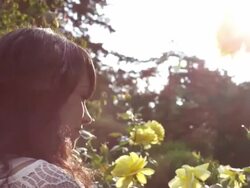 CU TS Shot of beautiful brunette smiles and smells rose on sunny day / Portland, Oregon, United States  Stock Footage