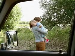 Mother hugging baby son, viewed from inside a car Stock Footage