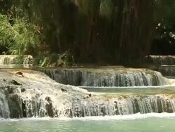 MS SLO MO Shot of Water flowing quickly with many small waterfalls around and vegetation in middle / Kuang Si, Luang Prabang, Laos Stock Footage