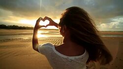 Caucasian female on beach makes heart shape finger frame Stock Footage