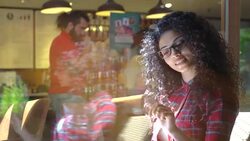Curly-haired pretty lonely student reading book and give to order at cafe Stock Footage
