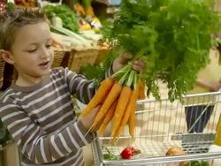 Boy holding bunch of carrots in supermarket Stock Footage