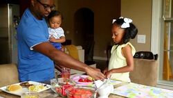 MS Father holding infant son while serving breakfast to daughter Stock Footage