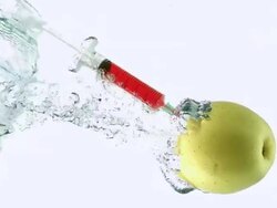 CU SLO MO Shot of Golden Apple, malus domestica, Fruit with Syringe entering Water against White Background / Calvados, Normandy, France Stock Footage