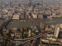 Aerial wide shot panning London cityscape and traffic around Thames and on London and Cannon Street Railway bridges / London, England Stock Footage