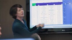 Insightful businesswoman leads meeting in corporate boardroom, gestures animatedly as data on big-screen moves Stock Footage