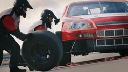 Pit-crew replaces race-car tire, man rolls old tire away Stock Footage