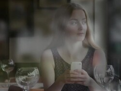 Using smartphone, young woman in a restaurant, view through a window. Stock Footage