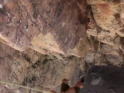 Handheld tilt of a rock-climber struggling up a cliff. Stock Footage