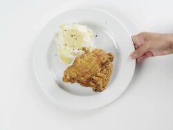 CU Woman hand entering setting down round white plate with fried chicken, mashed potatoes and gravy / Omaha, Nebraska, United States Stock Footage
