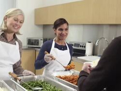 Women serving meals to people in soup kitchen Stock Footage