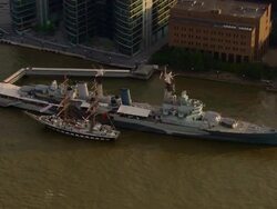 Aerial over HMS Belfast berthed on bank of Thames / London Stock Footage