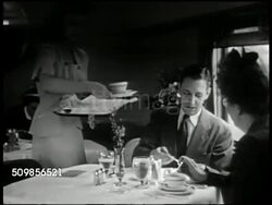 1947: U.S. LUXURY TRAINS: DINING: WS Passengers in dining car, waitress, waiter. MS Middle aged couple at table, waitress serving soup. MS Waitress. MS Mother w/ baby receiving tray from waiter. CU Tray of change. MS Man picking up change. Instructional Video