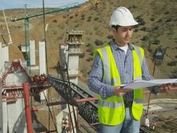 engineer checking plans on freeway bridge construction site, turning to camera at end of clip Stock Footage