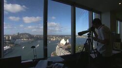 A man stands in front of a picture window and views Sydney Harbor with a telescope. Stock Footage