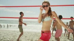 Confident woman on beach with friends playing volleyball Stock Footage