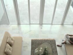 Elevated view of man on sofa reading newspaper and woman walking past Stock Footage