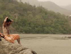Sage sitting at ganges riverbank, Rishikesh, Uttarakhand, India Stock Footage