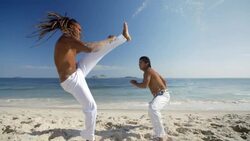 Brazilian capoeira martial artists trade kicks on beach in slow motion Stock Footage