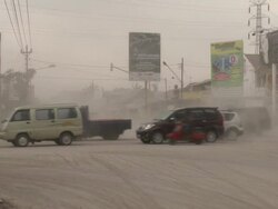 Traffic drives on intersection coated in thick layer of volcanic ash after eruption of Merapi volcano; Central Java, Indonesia. 30 October 2010 / AUDIO Stock Footage