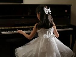 MS Rear view of girl wearing white dress, playing piano / China Stock Footage