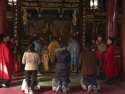 Worshipers kneel at an altar while priests chant and play instruments in the Bai Yun Guan Temple in Beijing. Stock Footage