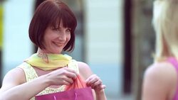 Female friends checking shopping bags over coffee on sunny day Stock Footage