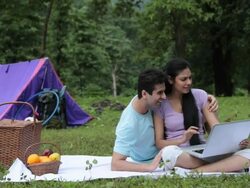 Young couple working on a laptop in a forest, Malshej Ghat, Maharashtra, India Stock Footage