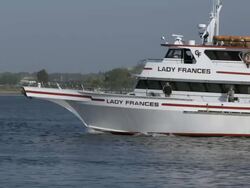 Whale watching boat passing pier and fishing boats as it leaves the harbor Stock Footage