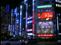 MWA traffic moving in front of wall of neon advertising on building, Shinjuku west district, Tokyo, Japan Stock Footage