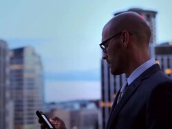 MS Businessman working on smart phone standing on deck looking out over cityscape at night/Seattle, Washington, USA Stock Footage