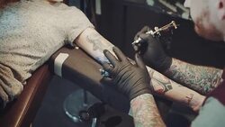 Tattoo artist tattooing young woman Stock Footage
