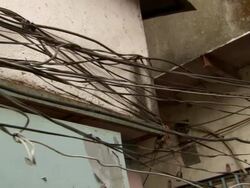 MS PAN  Electric power cables hanging  in bunches and tangled on side of buildings / India Stock Footage
