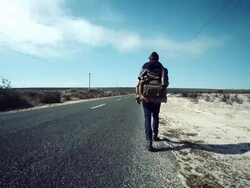 Backpacker walking along road Stock Footage