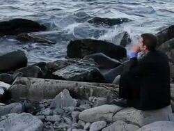 MS Man sitting on rocks looking out over ocean / Portland, ME, United States Stock Footage