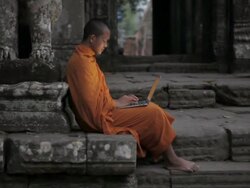 WS A Buddhist monk uses a laptop computer on the steps of an ancient temple in Angkor Wat / Siem Reap, Cambodia Stock Footage